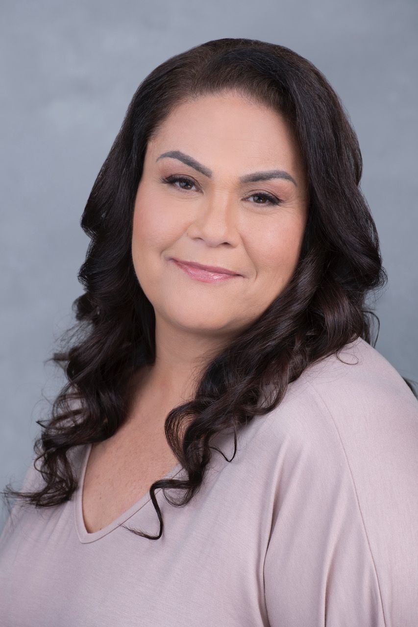 A woman in a pink shirt is smiling for the camera.