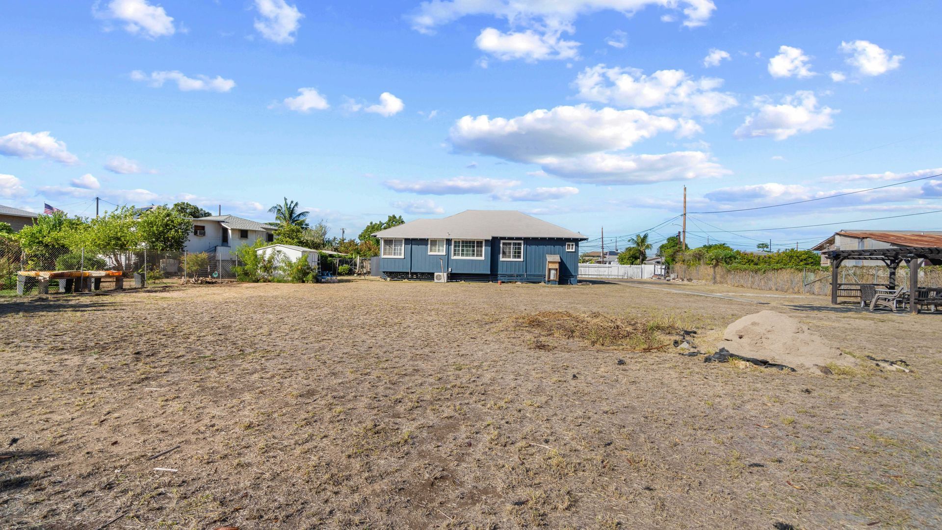 A blue house is sitting in the middle of a dirt field.