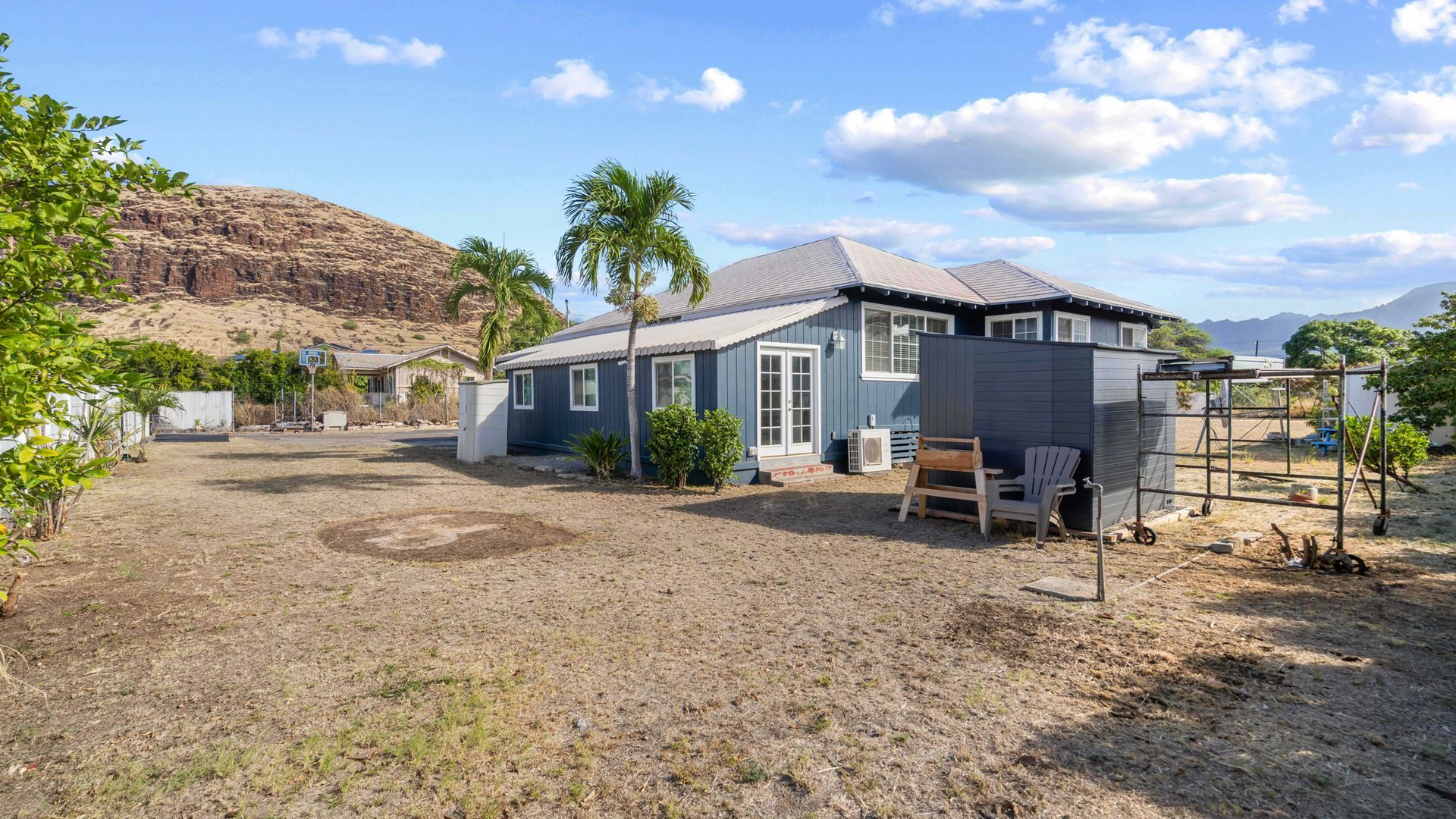 A house is sitting in the middle of a dirt field with a mountain in the background.