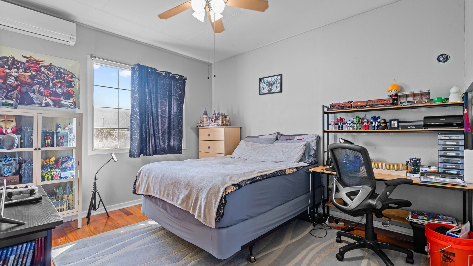 A bedroom with a bed , desk , chair and ceiling fan.
