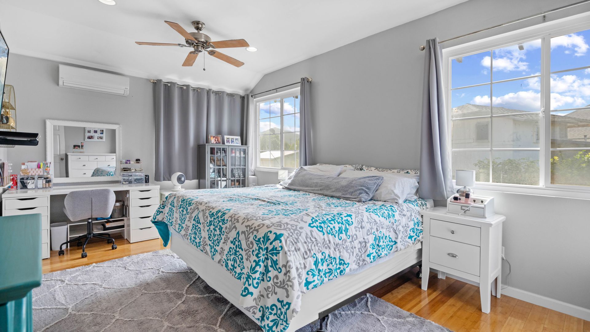 A bedroom with a bed , desk , nightstand , and ceiling fan.