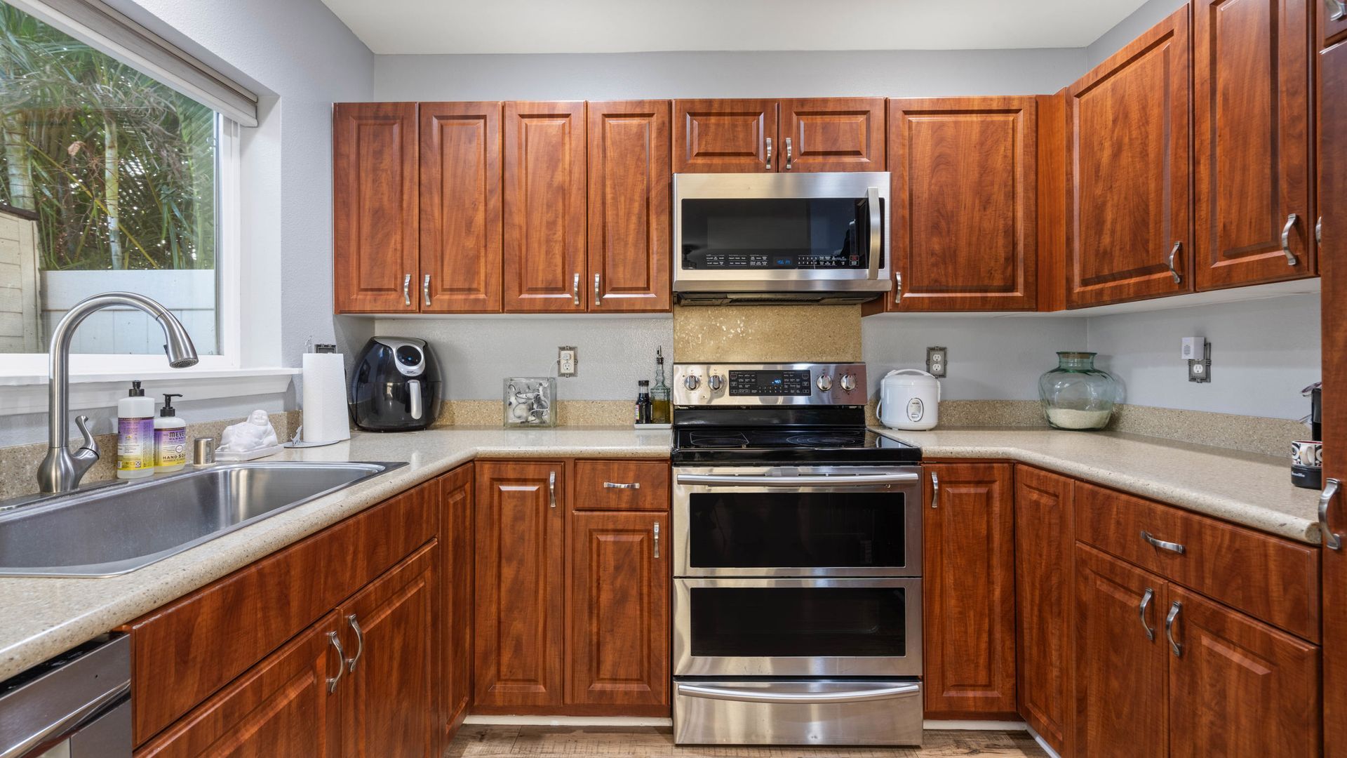 A kitchen with wooden cabinets , stainless steel appliances , a sink , and a window.
