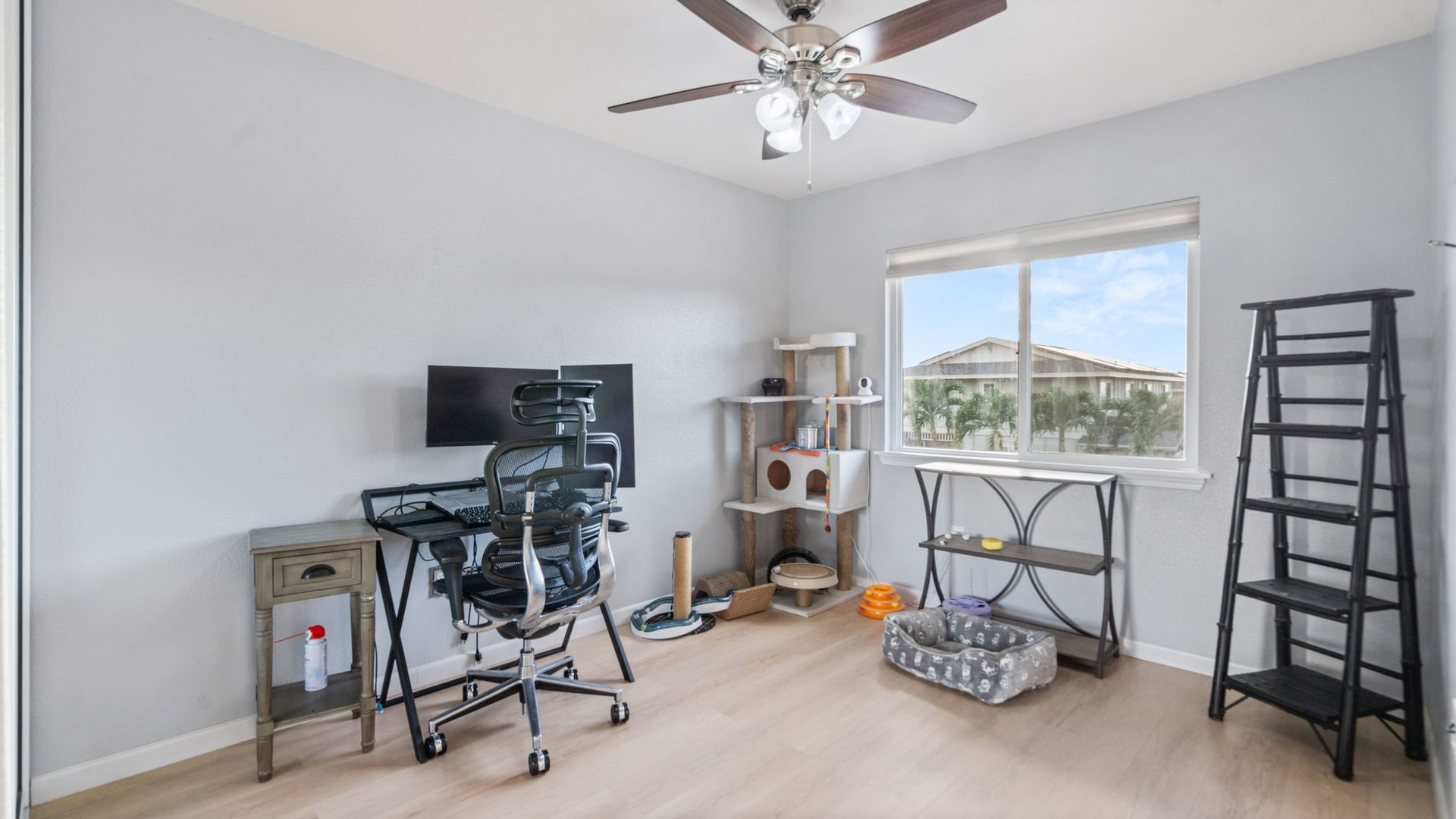 A bedroom with a desk , chair , computer and ceiling fan.
