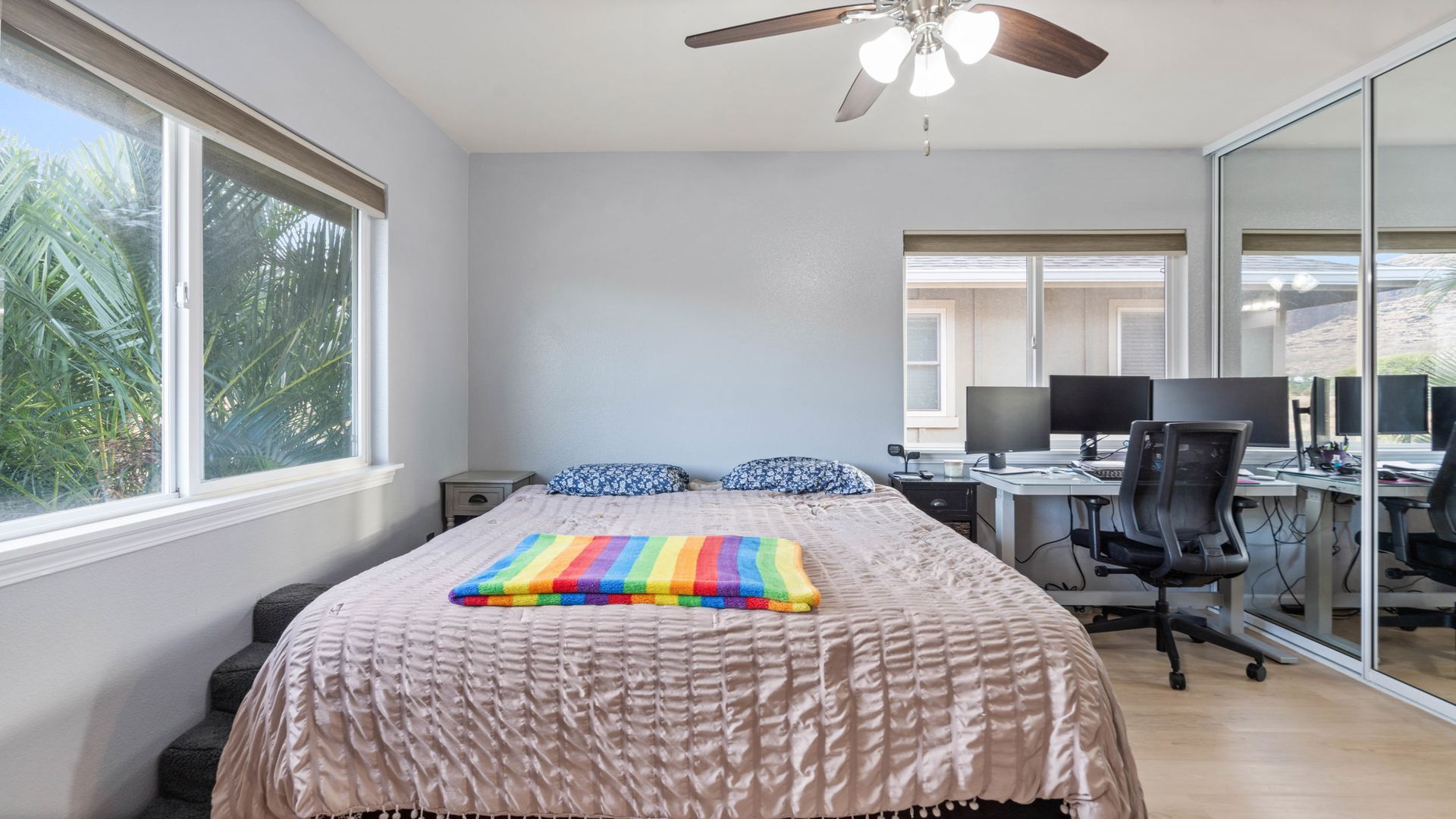 A bedroom with a large bed , a desk and a ceiling fan.