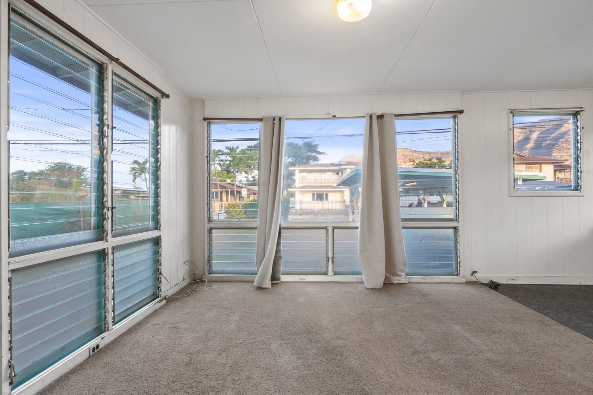An empty room with a lot of windows and curtains