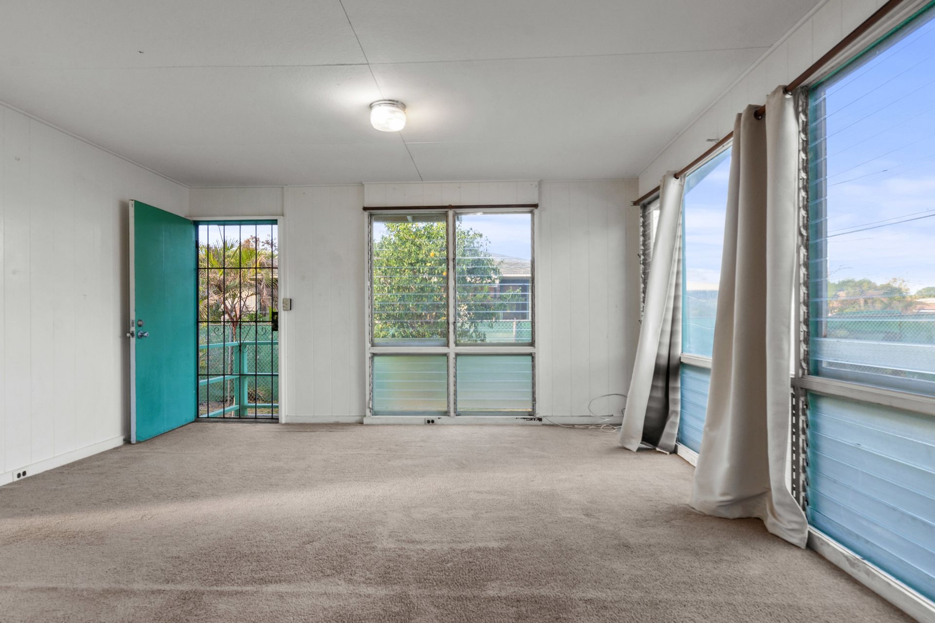 An empty room with a blue door and a lot of windows
