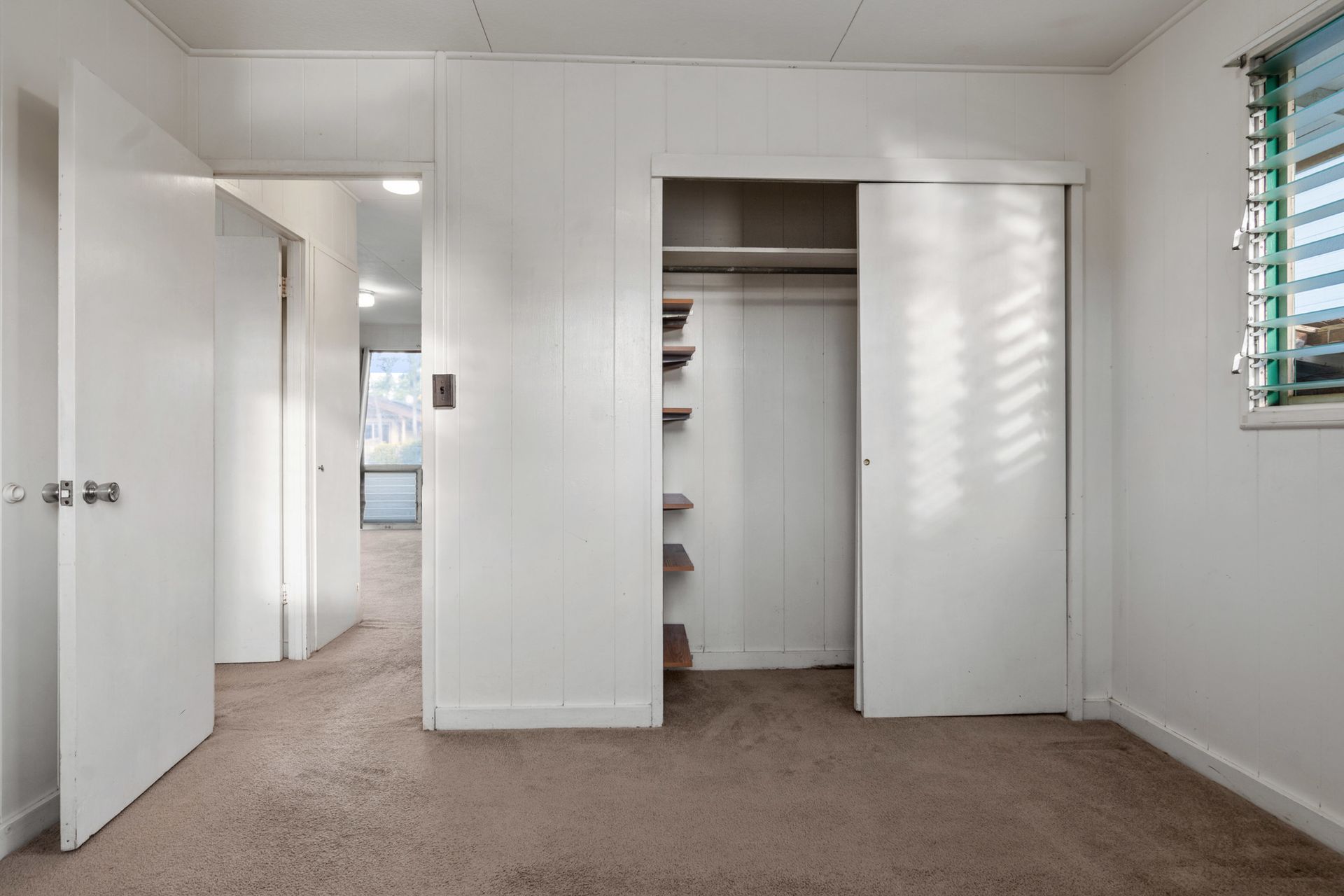 An empty bedroom with a closet and a window