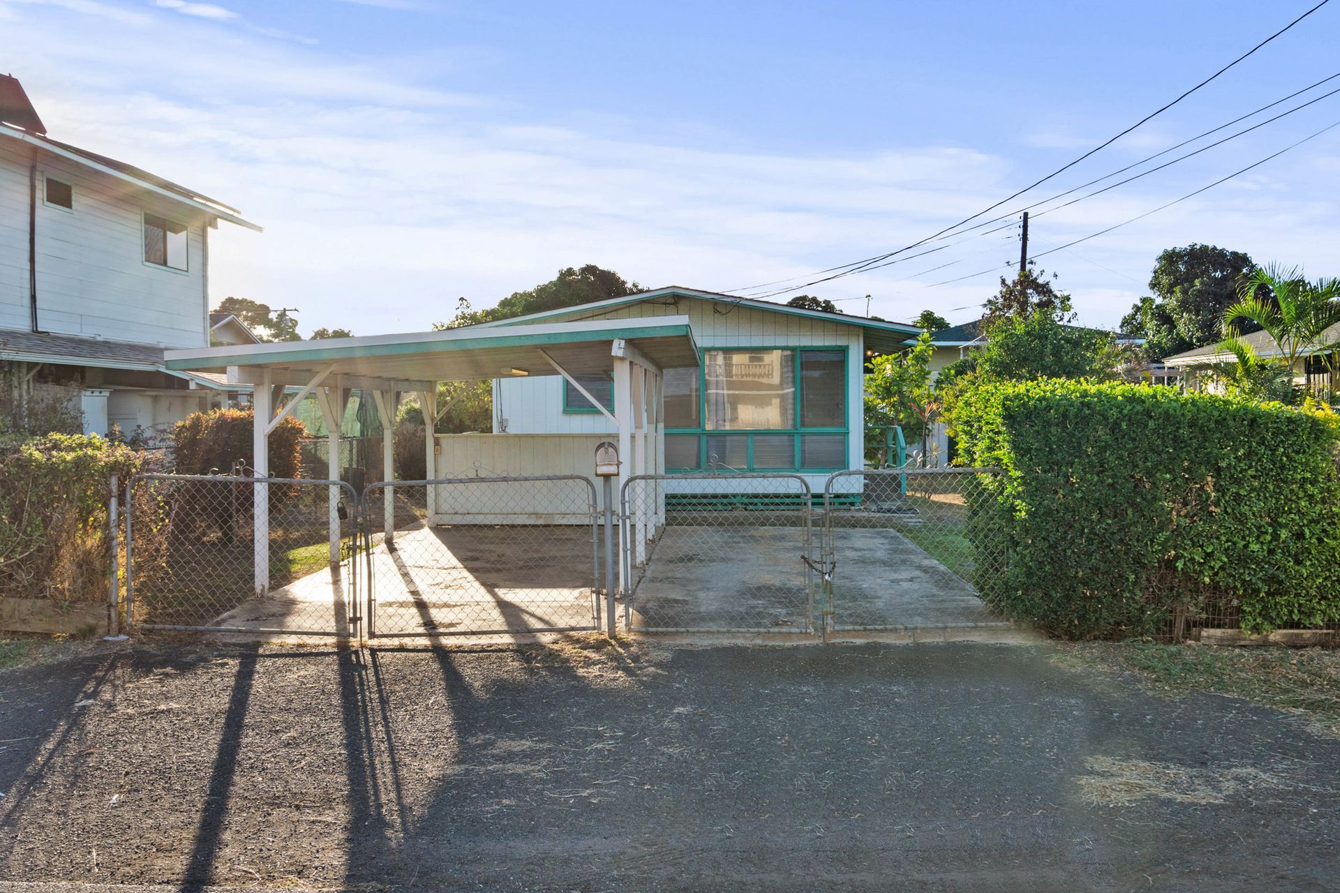A small house with a carport and a fence in front of it.