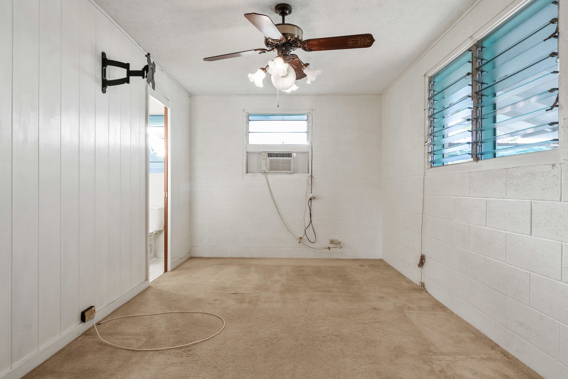 An empty room with a ceiling fan and a window.