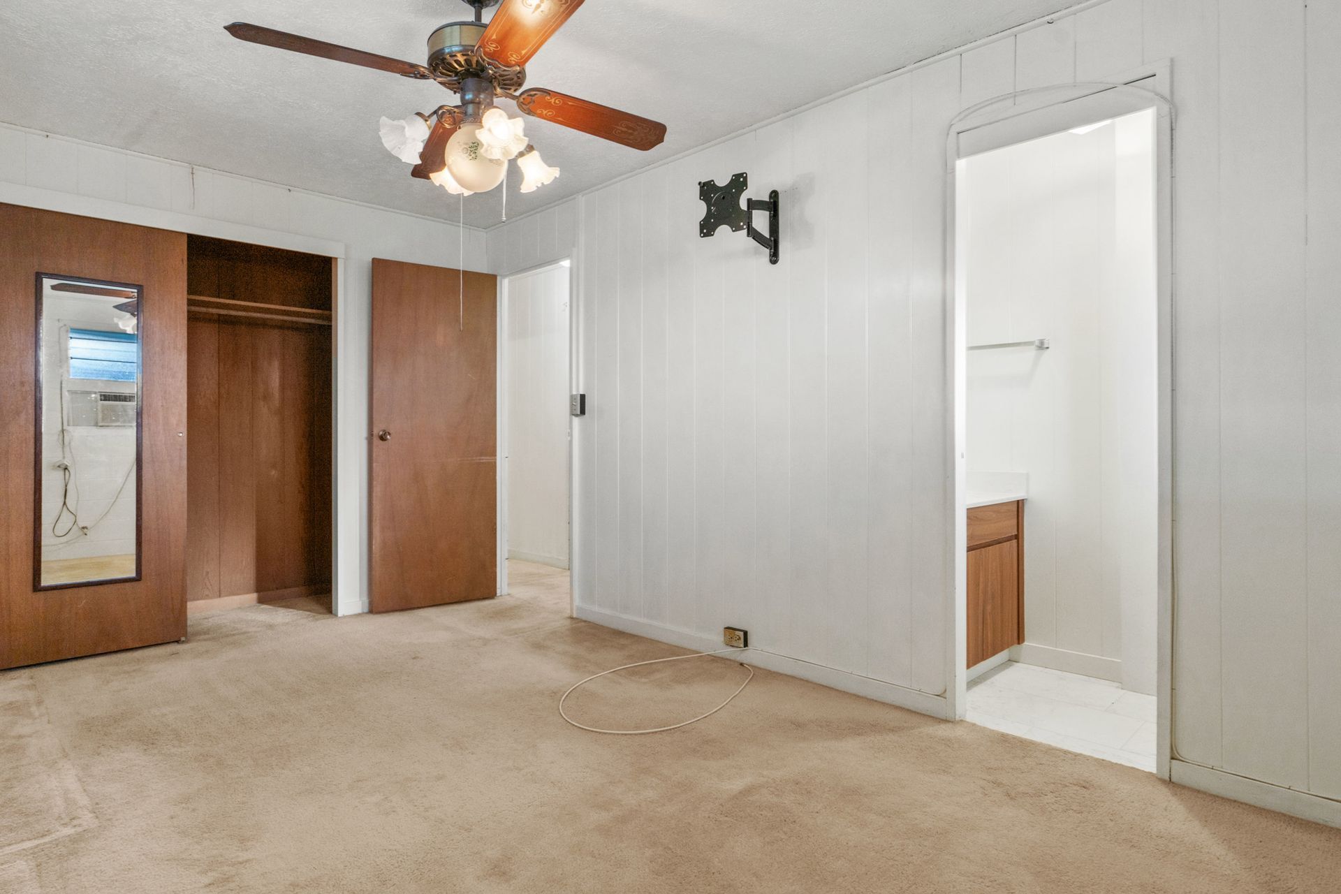 A bedroom with a ceiling fan and a mirror.