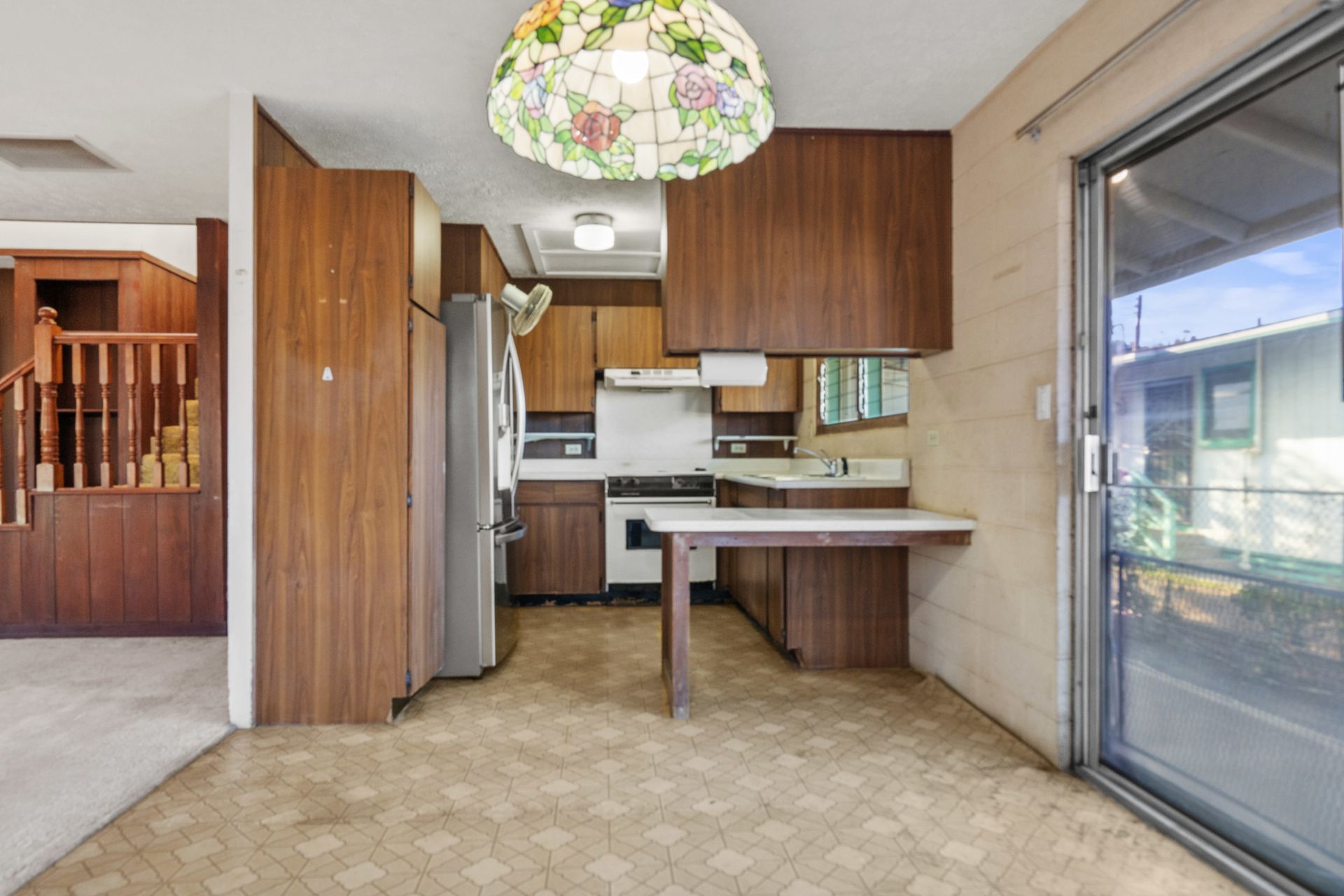 A kitchen with a sliding glass door and a lamp hanging from the ceiling.