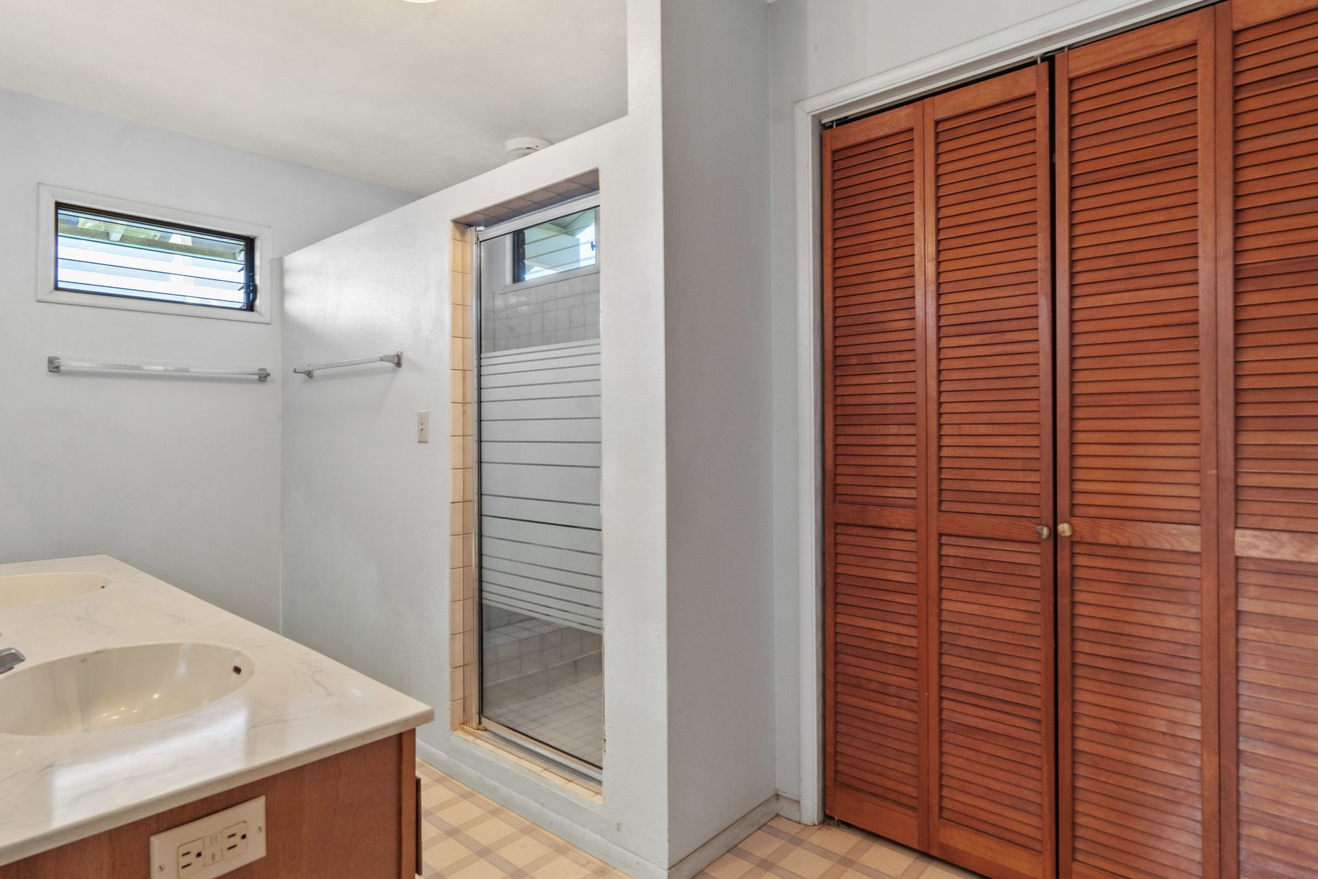 A bathroom with a walk in shower , sink , and closet.