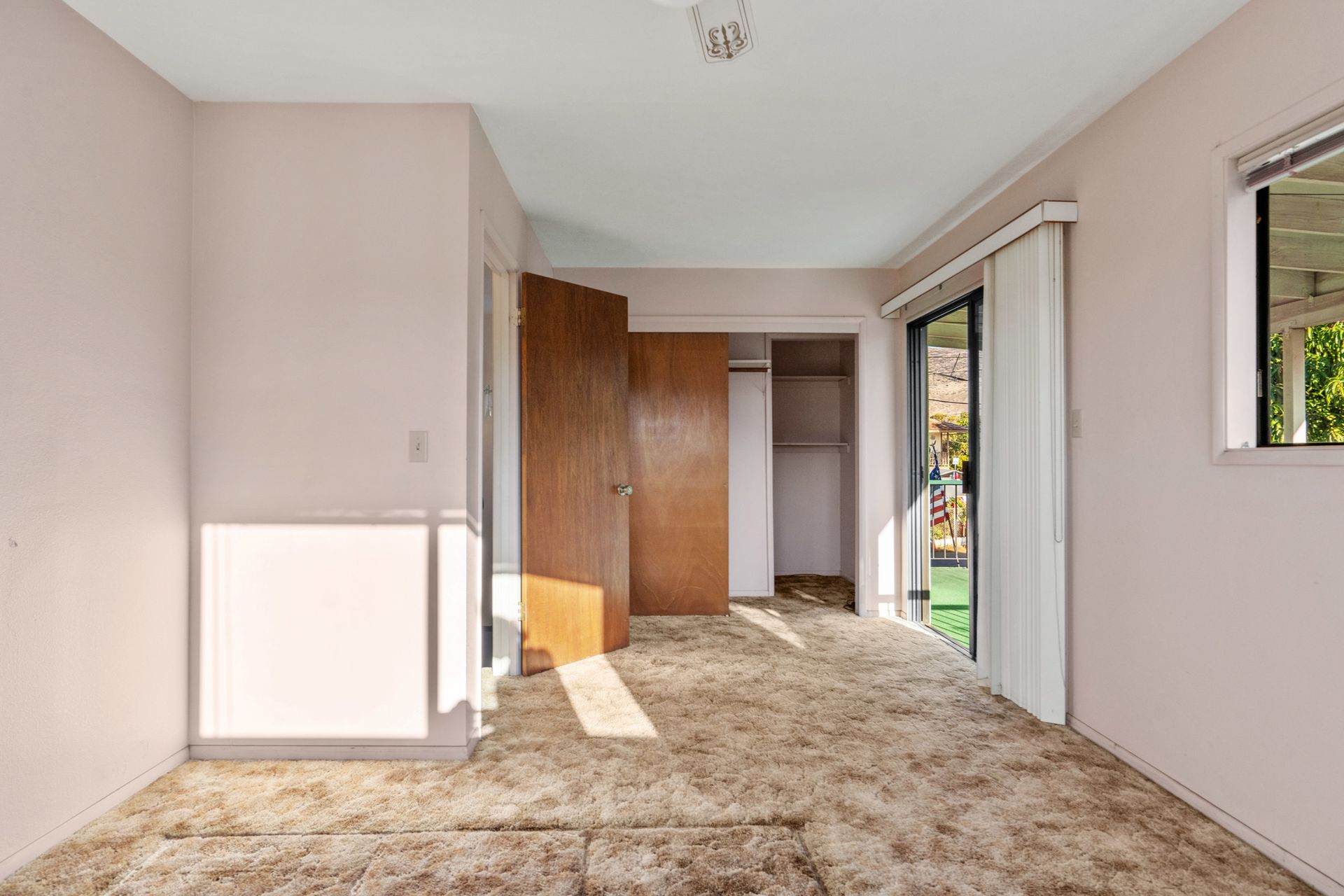 An empty room with a carpeted floor and a window.