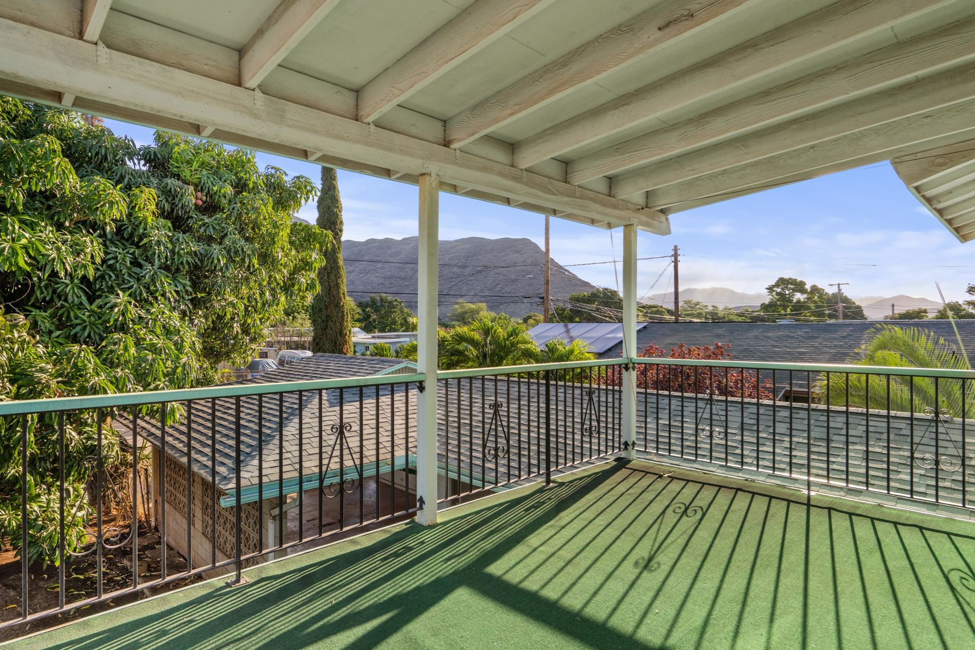 There is a balcony with a view of a mountain and trees.