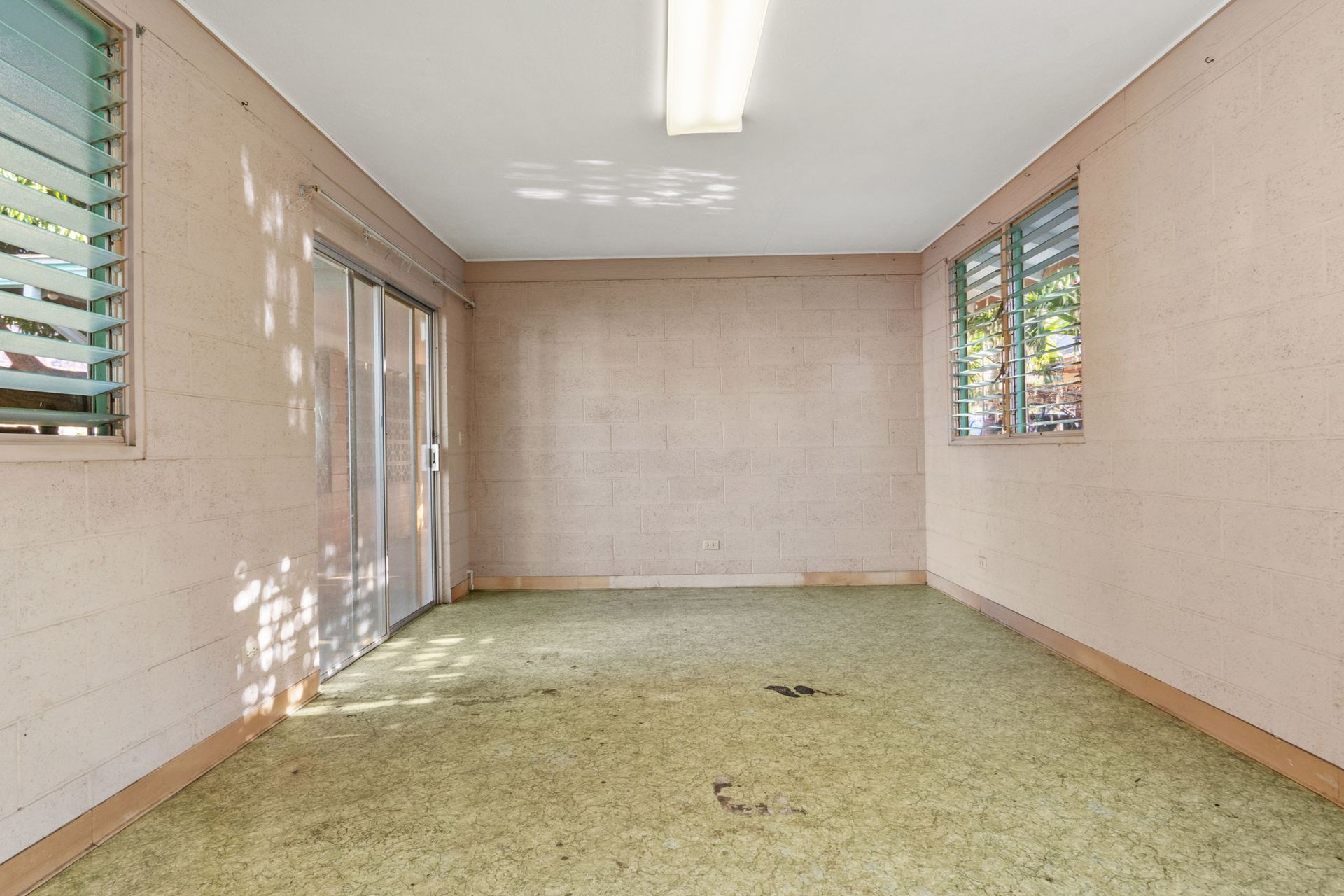 An empty room with a green carpet and two windows