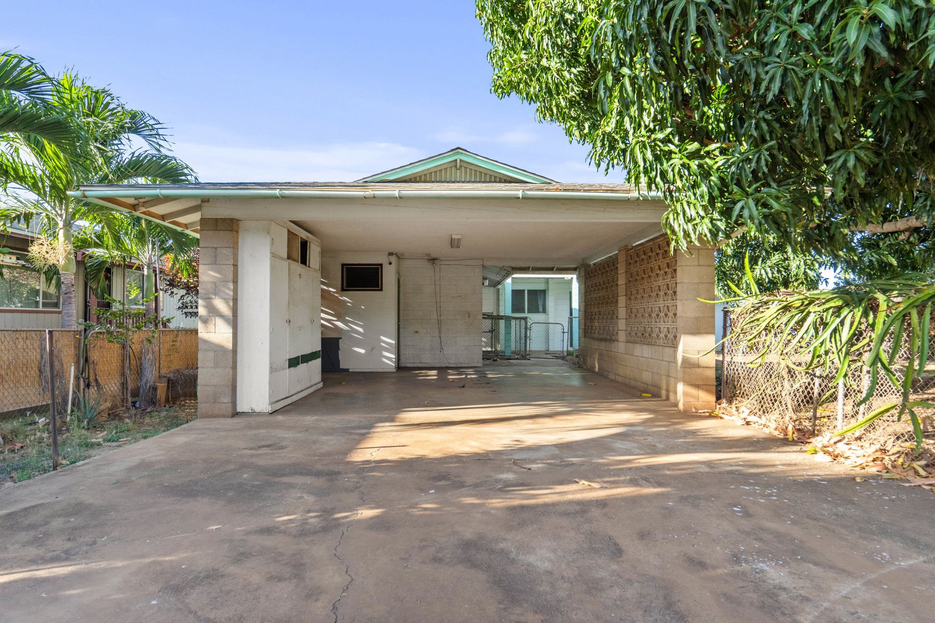 A house with a carport and a tree in front of it.