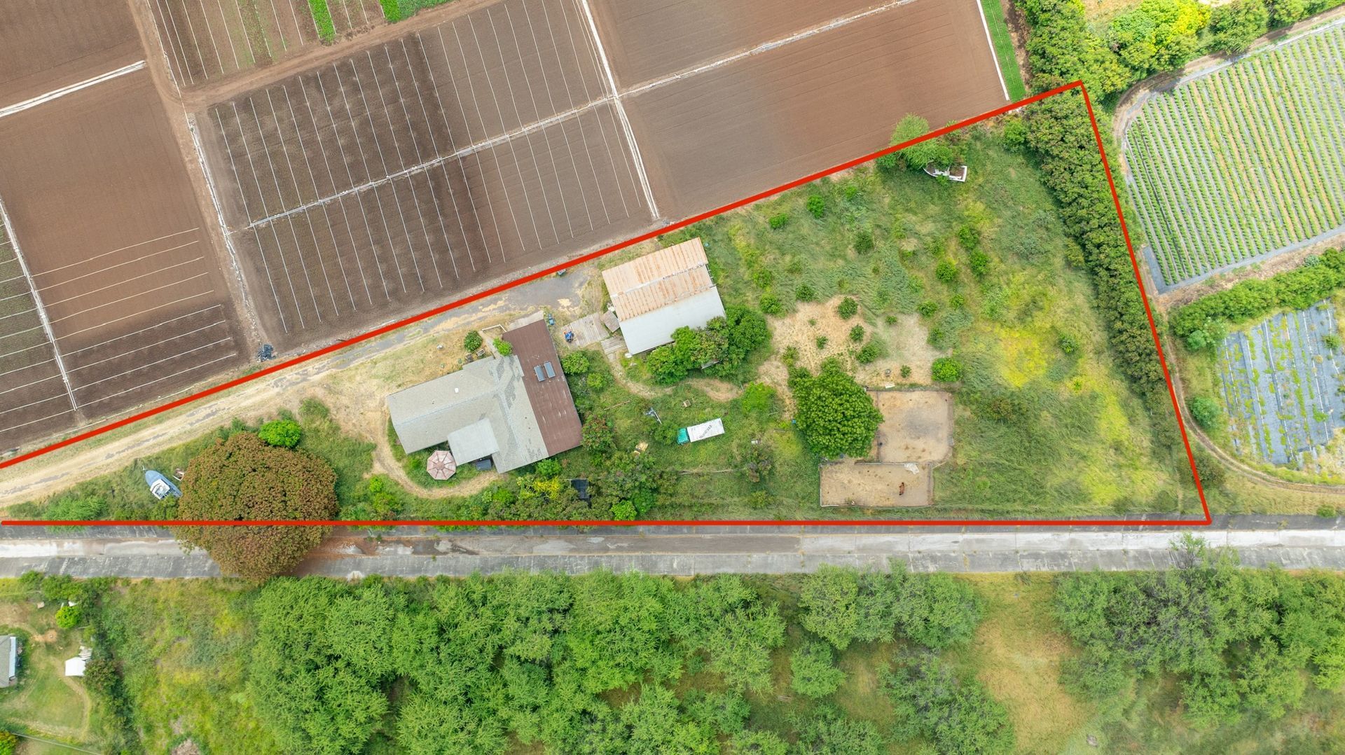 An aerial view of a house surrounded by fields and trees.