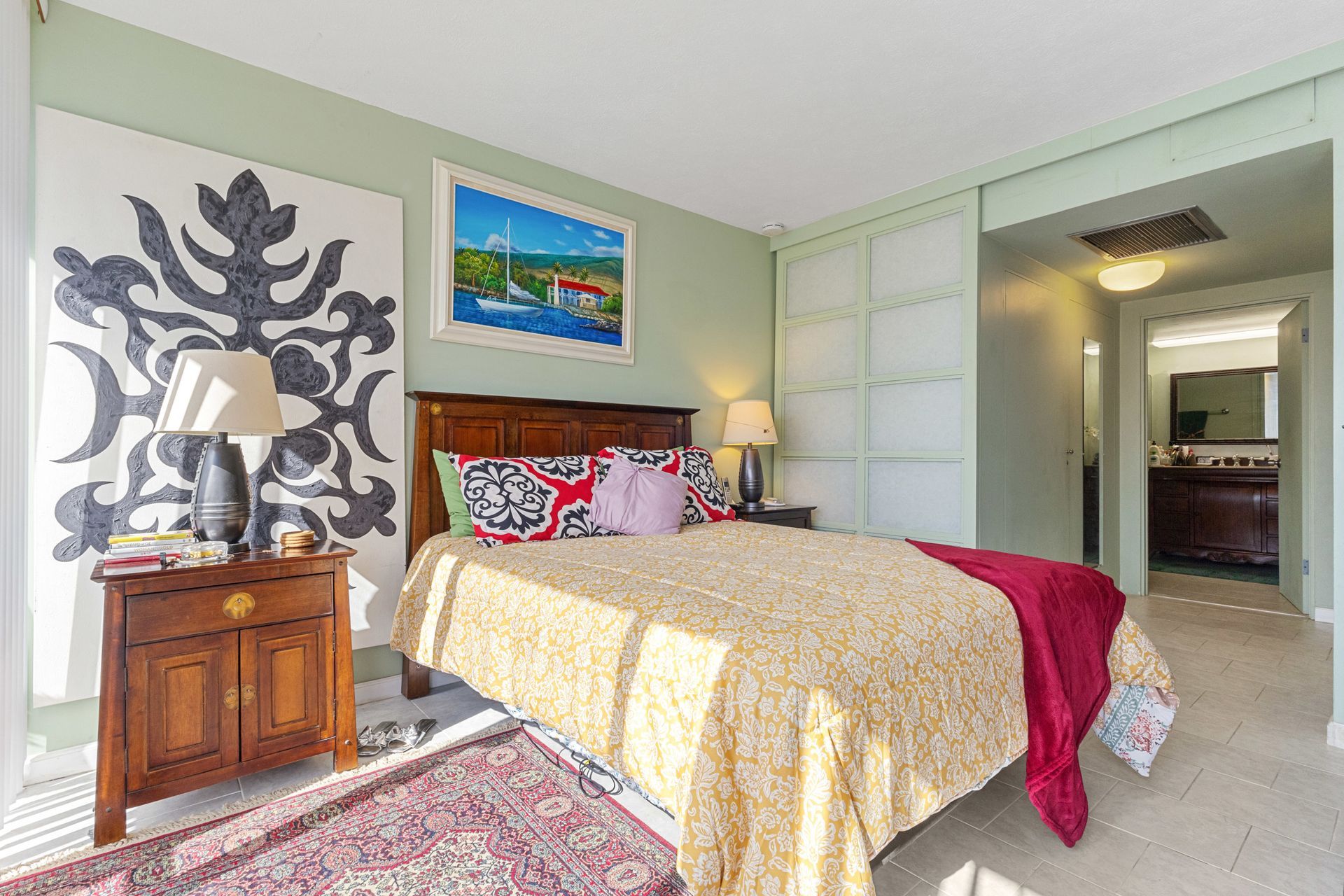 A bedroom with a king size bed , nightstand , lamp and sliding glass doors.