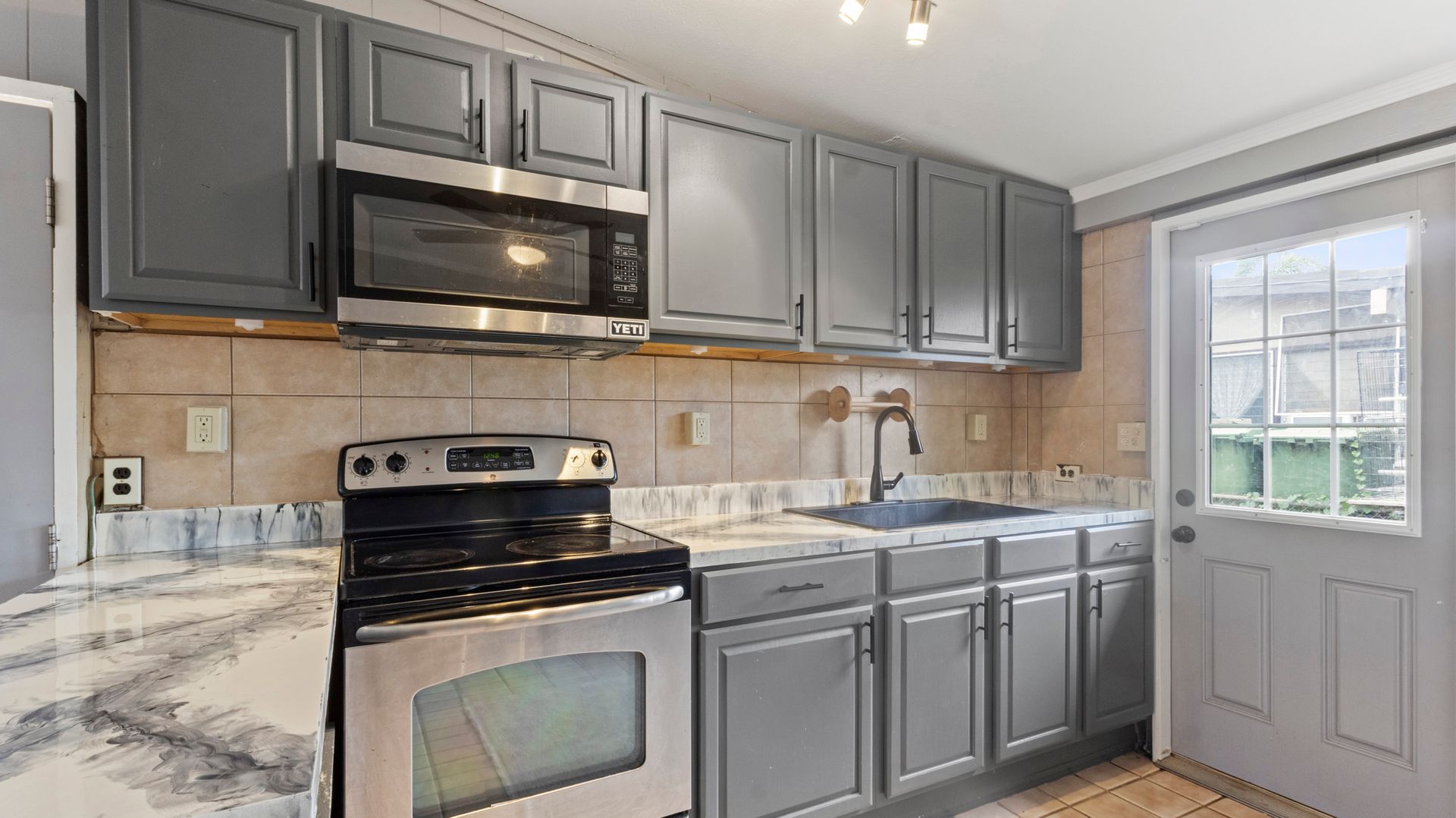 A kitchen with gray cabinets and stainless steel appliances