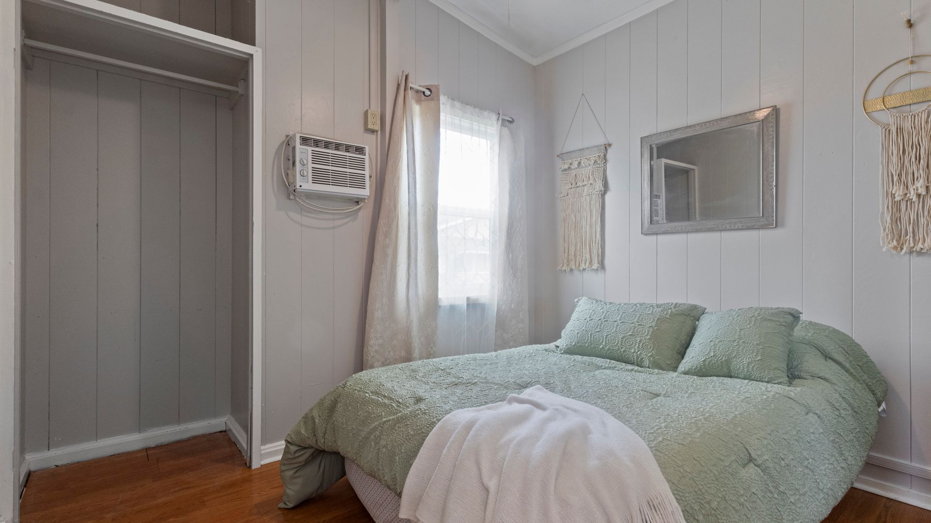 A bedroom with a bed , closet , mirror and window.