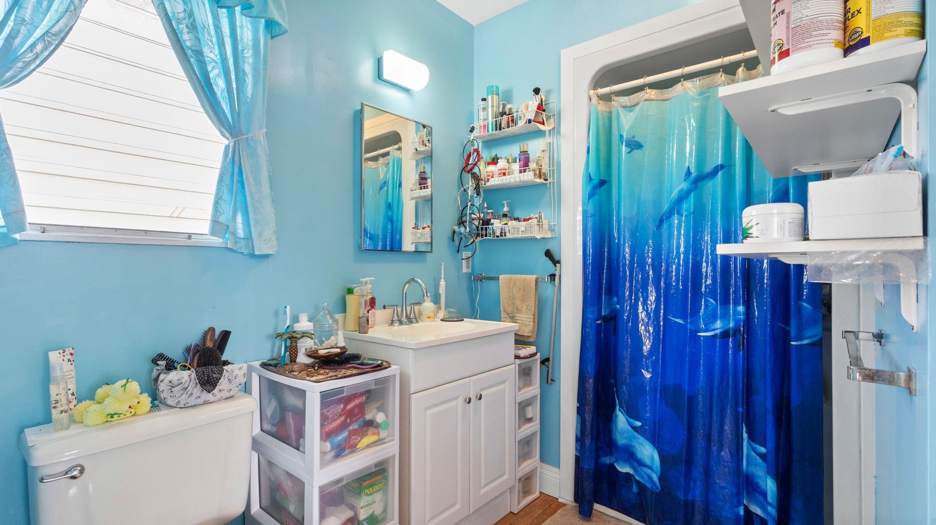 A bathroom with blue walls and a blue shower curtain.