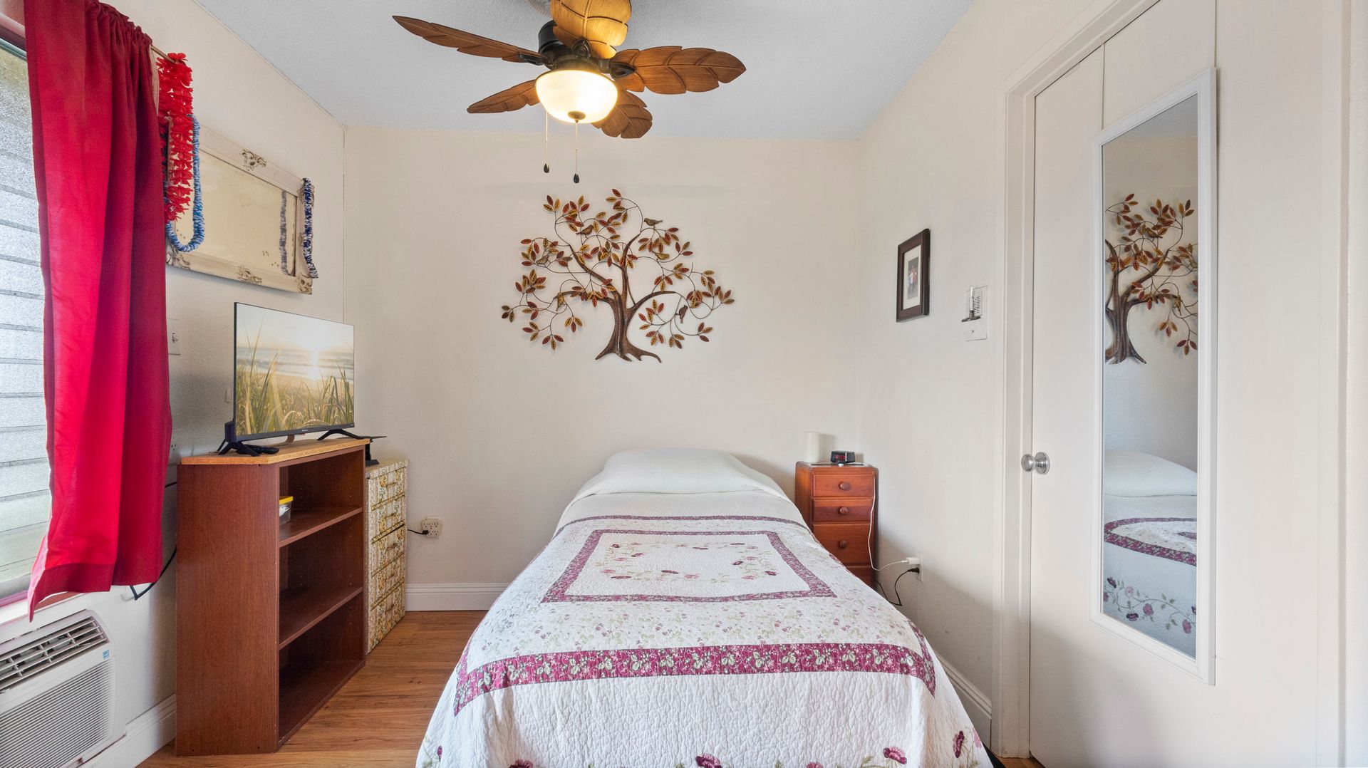 A bedroom with a single bed and a ceiling fan.
