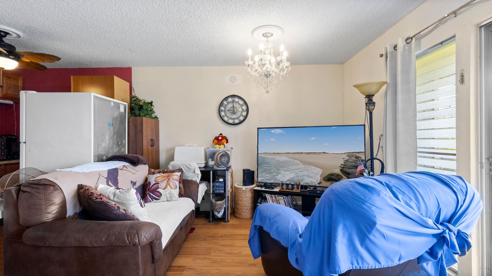 A living room with a couch , chair , television and a clock on the wall.