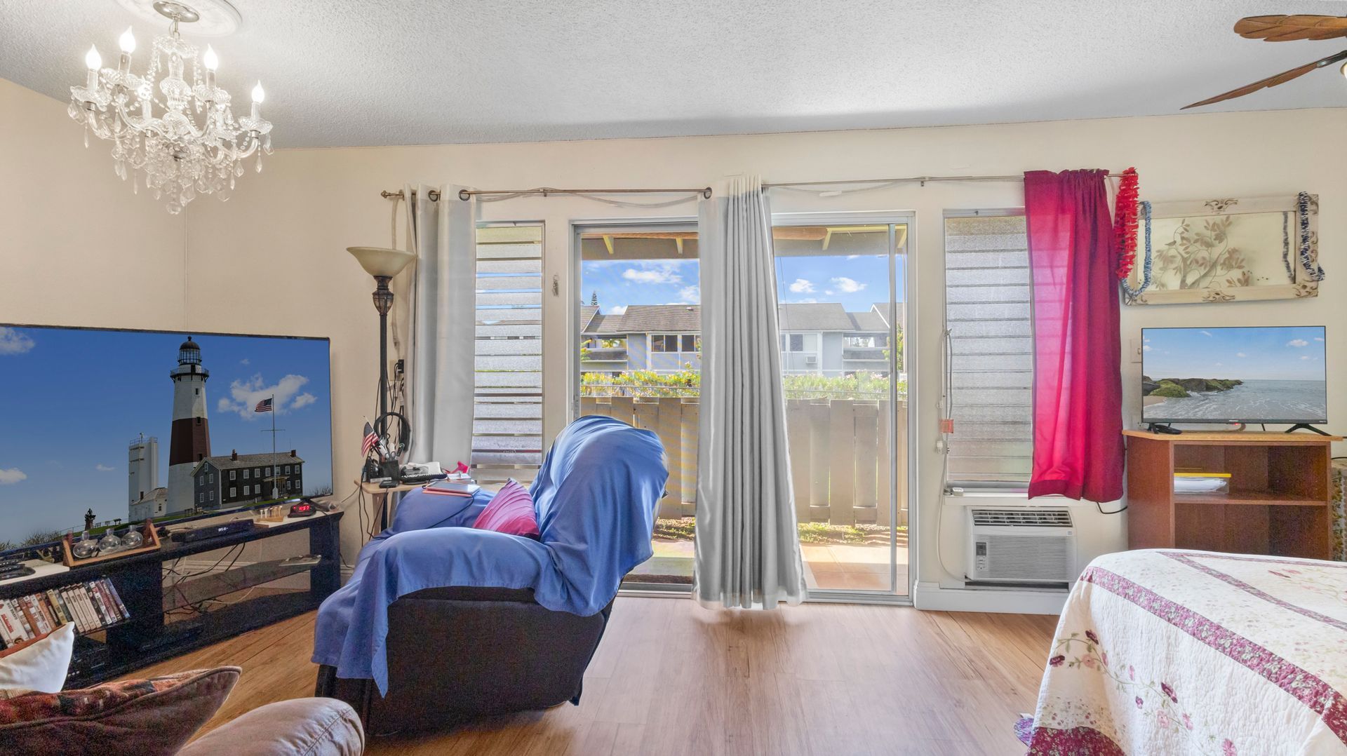 A living room with a couch , chair , television and sliding glass doors.