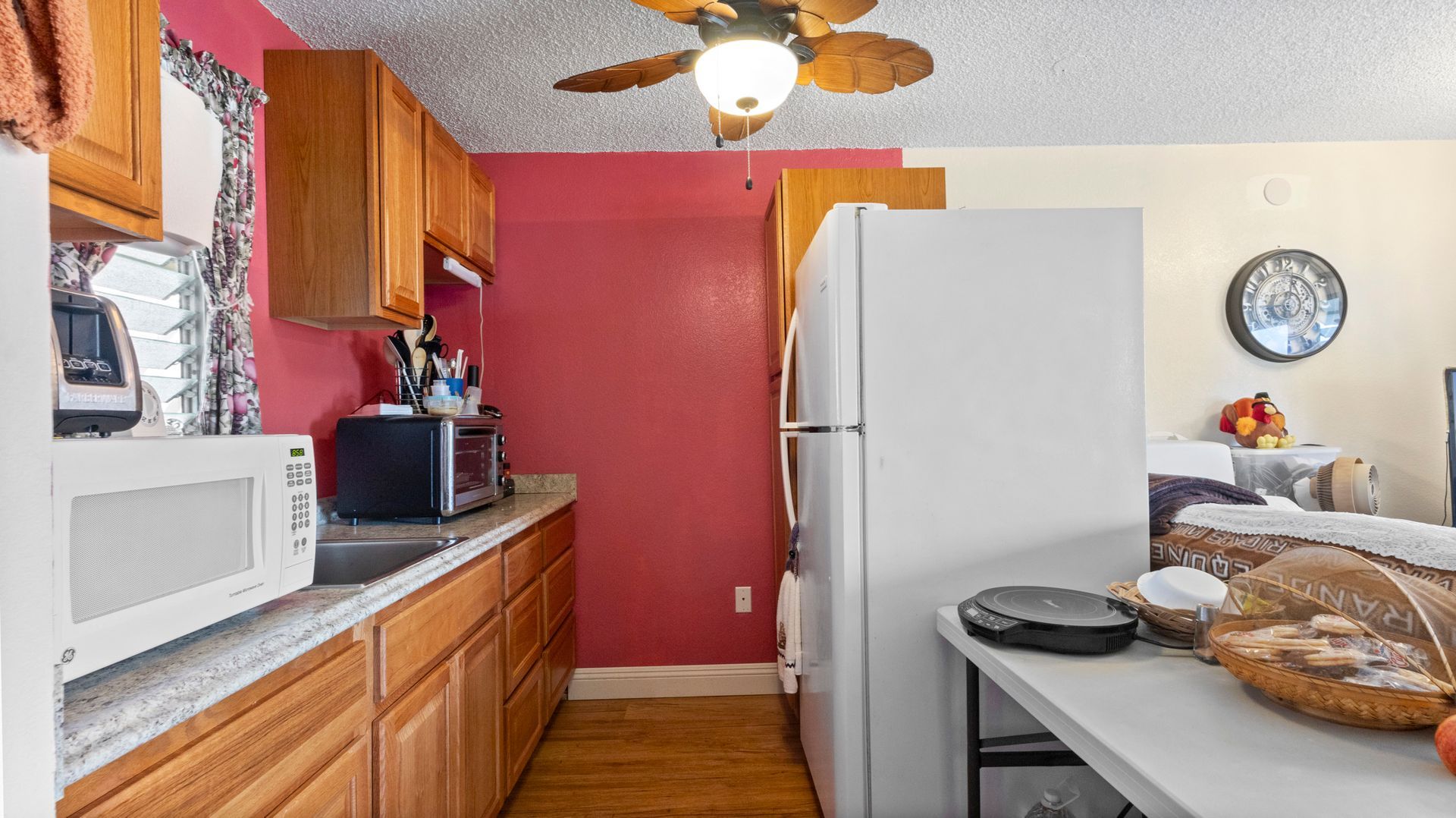 A kitchen with a refrigerator , microwave , and ceiling fan.