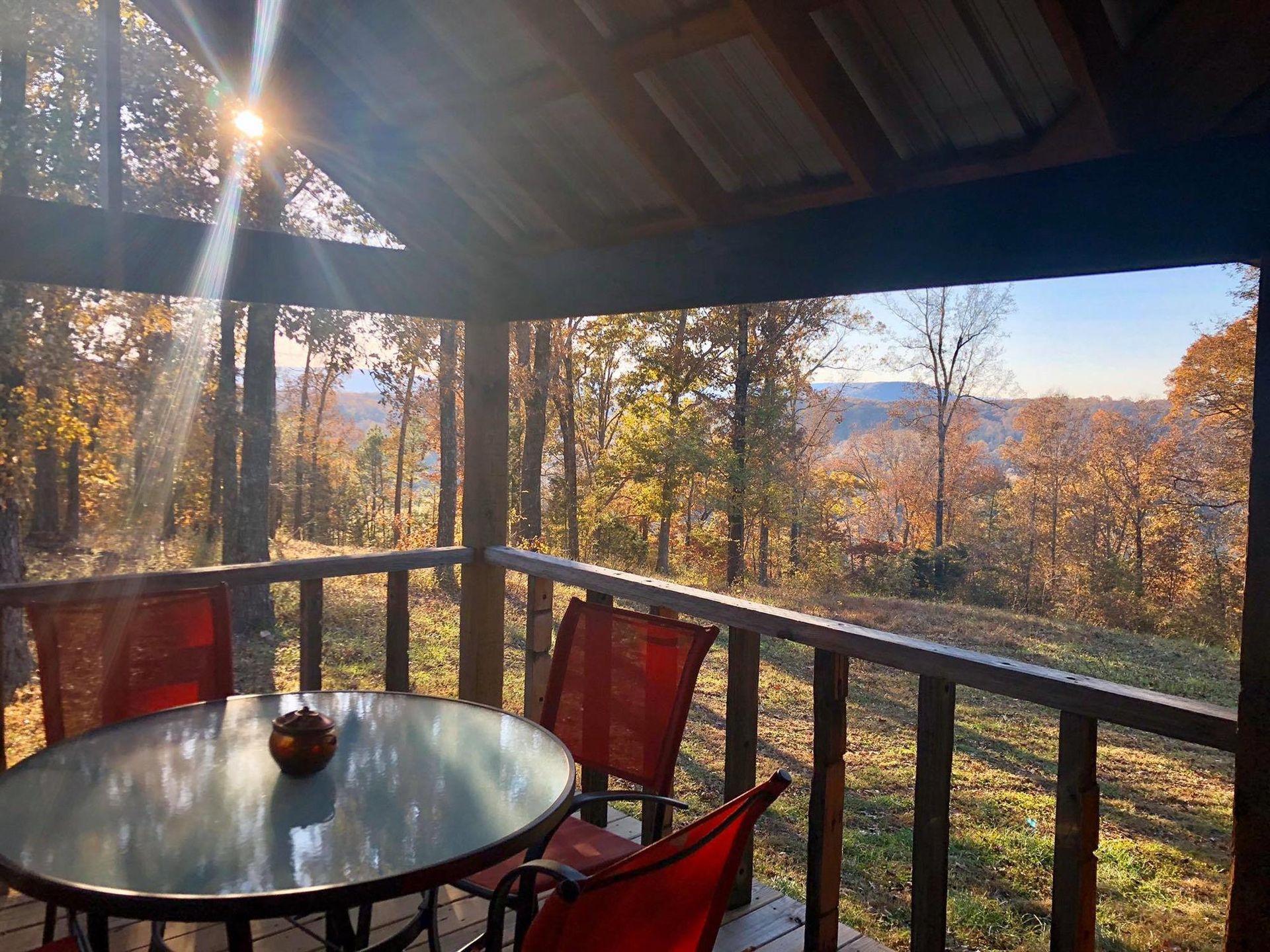 Covered porch overlooking fall foliage and mountain view; table, chairs.