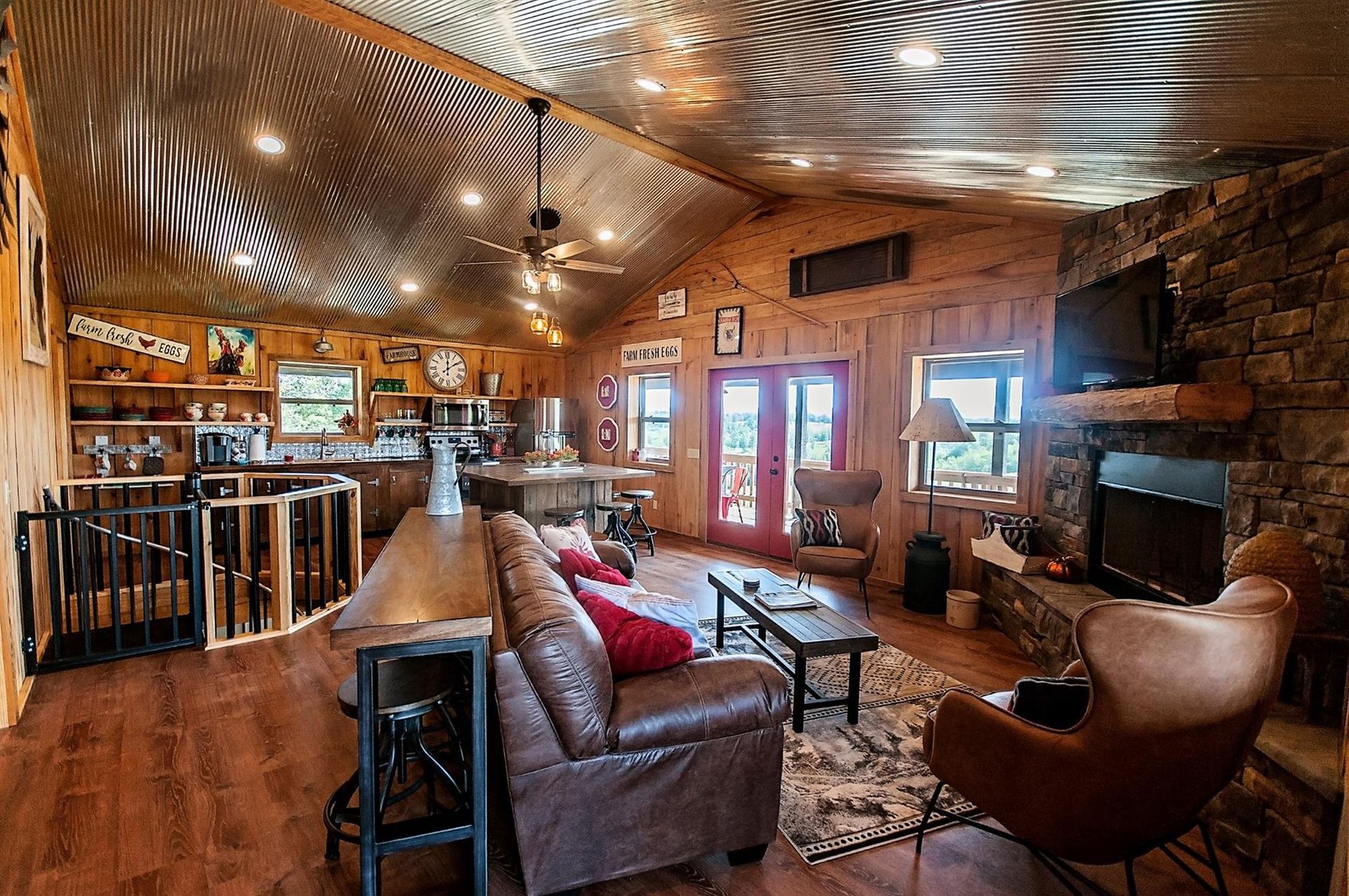 Rustic-style living room with metal ceiling, wood walls, fireplace, leather furniture, and a bar area.