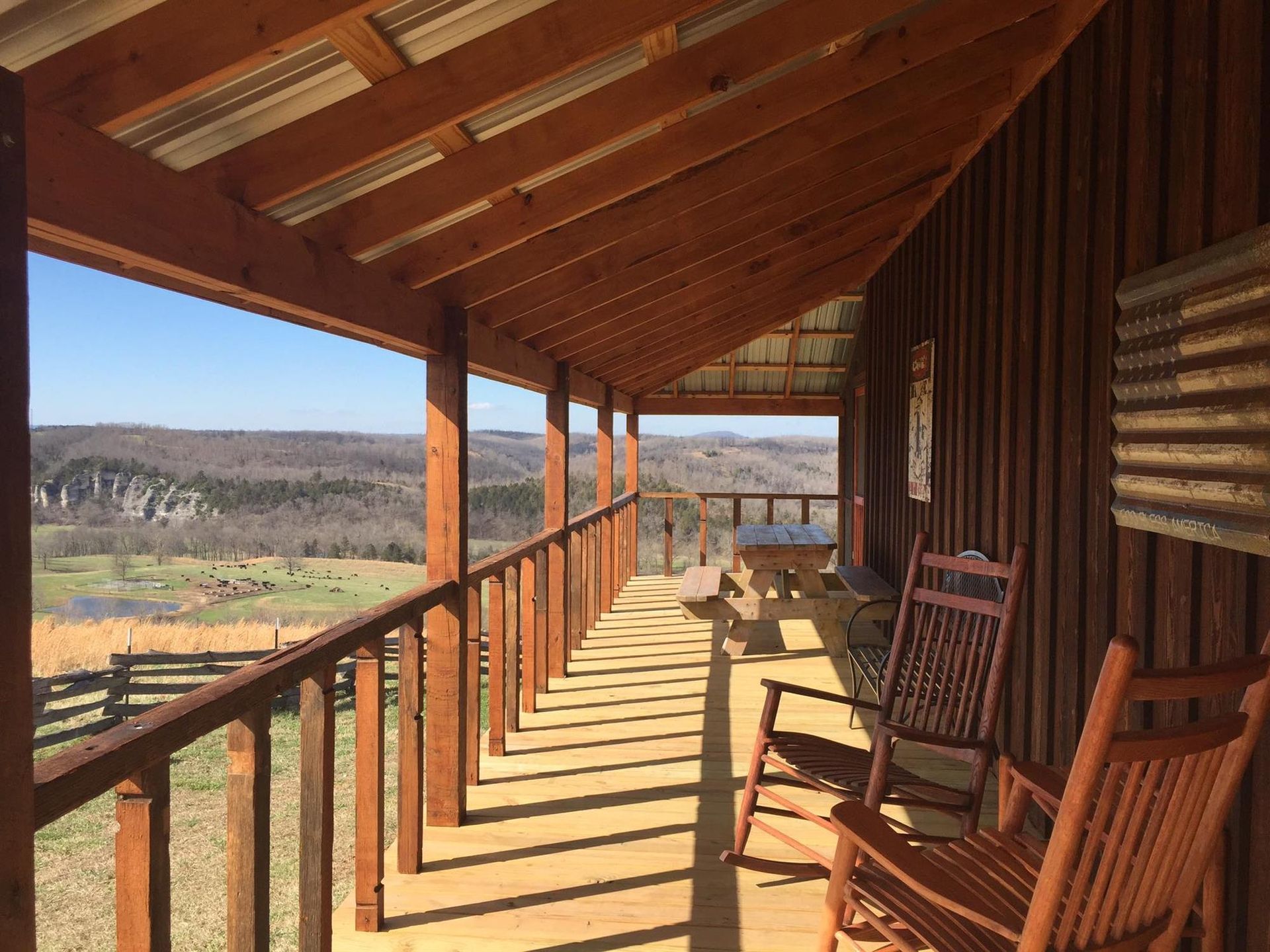 Wooden cabin porch with rocking chairs overlooking a scenic landscape.