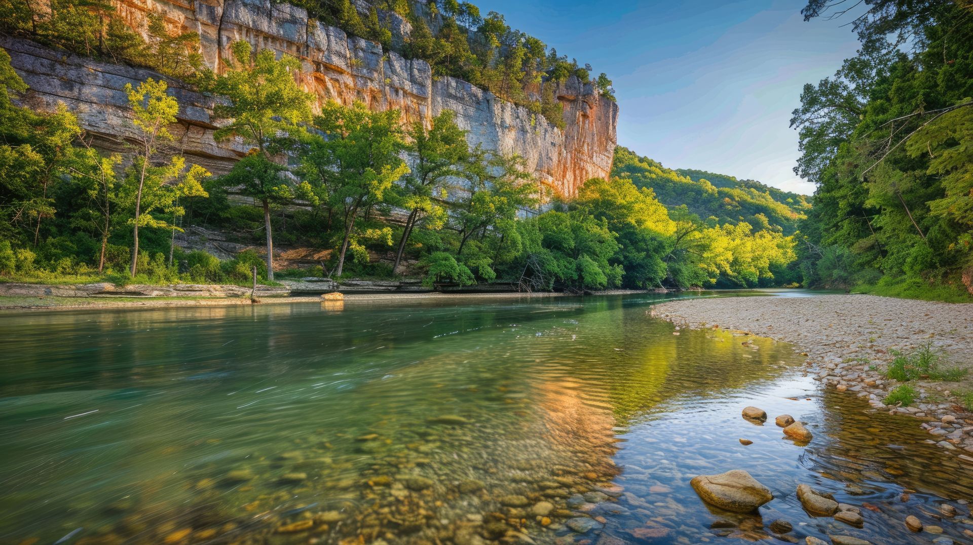 River flowing through a rocky landscape, with a large cliff face and trees.