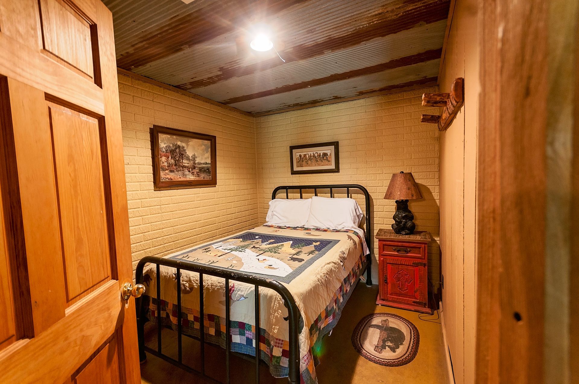Bedroom with single bed, rustic décor, wood paneling, artwork, and corrugated metal ceiling.