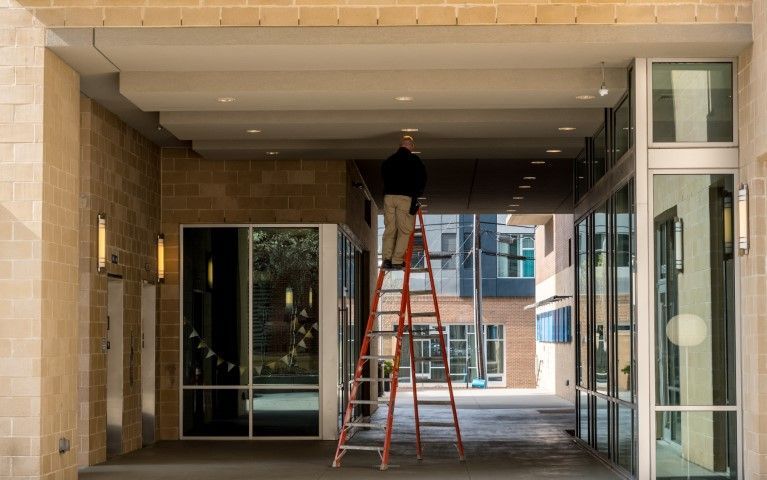 A man is standing on a ladder in front of a building.