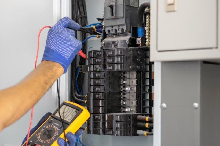 A man is using a multimeter to test an electrical box.