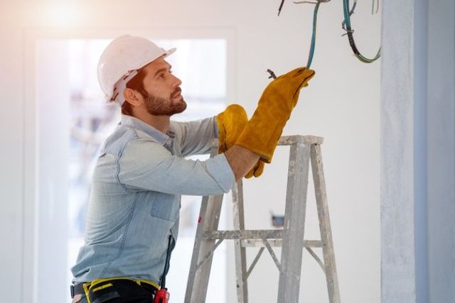 A man is standing on a ladder working on a wall.