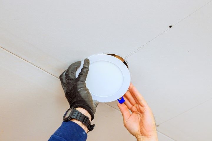 A person is installing a light fixture in a ceiling.