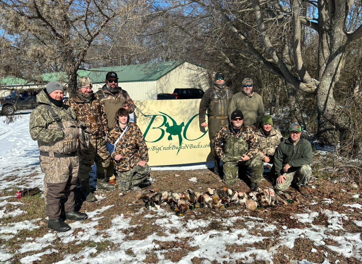 A group of hunters are posing for a picture in the snow.