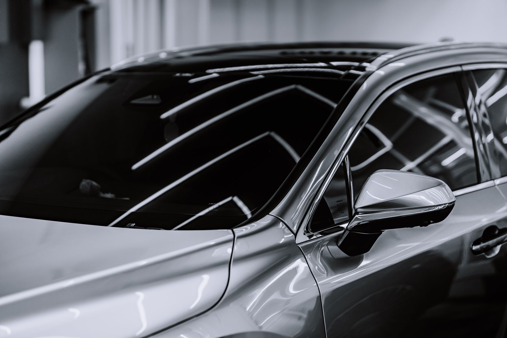 A black and white photo of a silver car parked in a garage