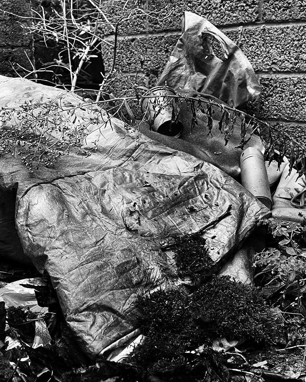 An empty sleeping bag,  lies in a forgotten alley corner. Painted entirely in gray, the piece evokes the invisible presence of the unhousedoverlooked.