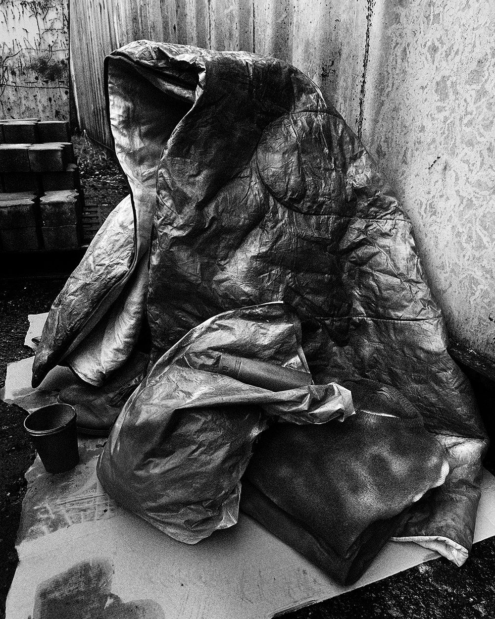 An empty sleeping bag, carefully posed to resemble a sitting body, a haunting tribute to lives often overlooked.