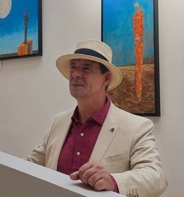 Anthony Carey standing beside a large abstract painting at an exhibition opening