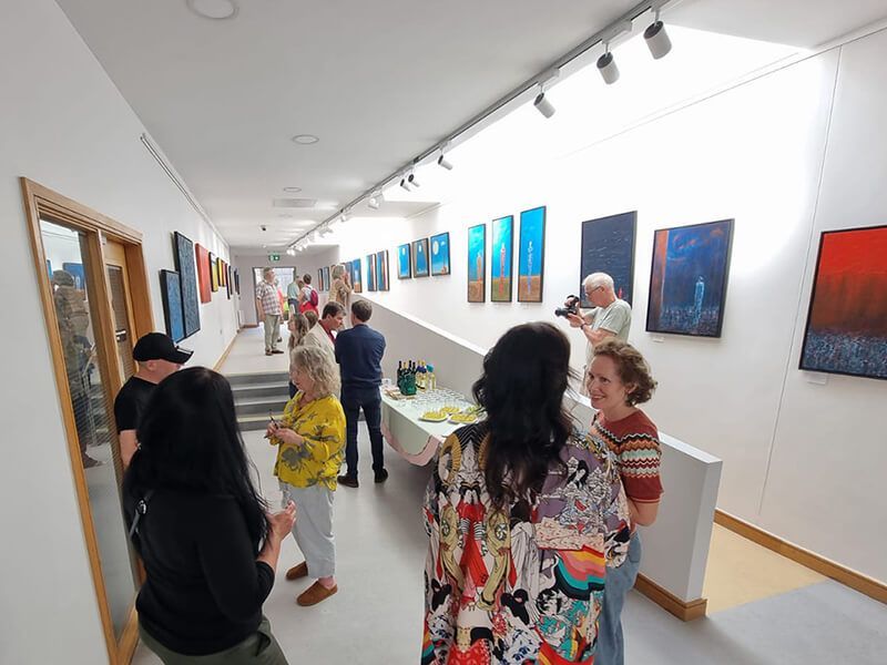 Groups of people stand discussing the abstract paintings on show