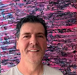 Anthony in front of one of his paintings Anthony Carey in front of his painting ‘Midnight on Jacaranda Boulevard’ - heavily textured work in purples, magentas, and dark blues.