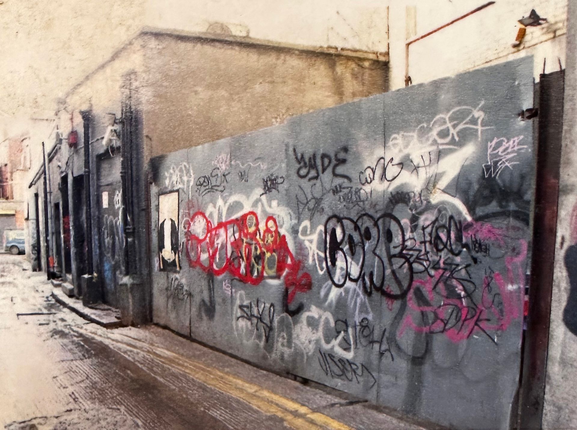 Grubby, derelict laneway in Dublin. Boarded up buildings covered in graffiti and dirt.