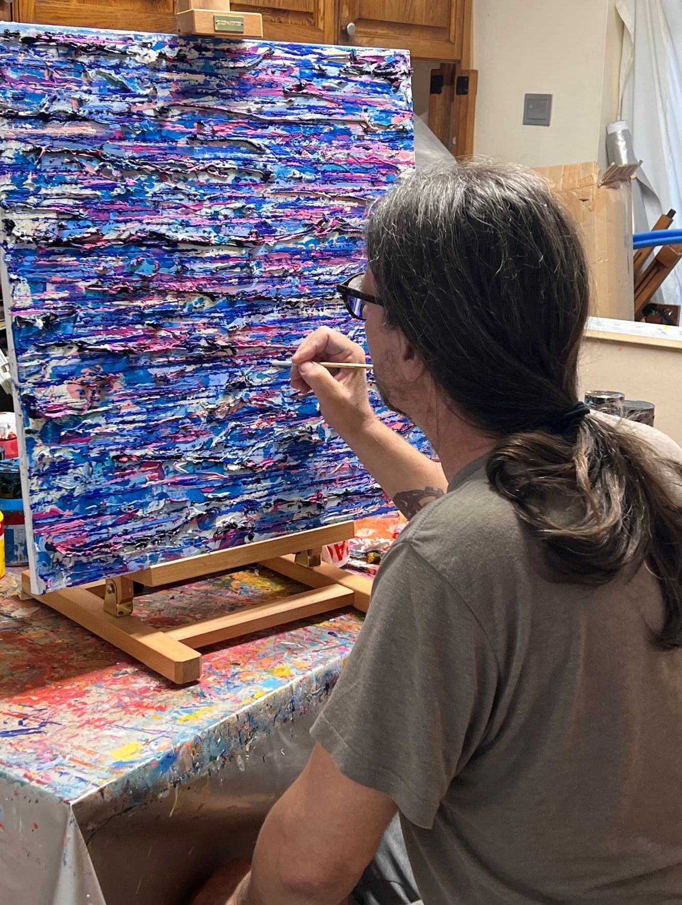 Headshot of white male artist with long hair working in the studio on an abstract painting