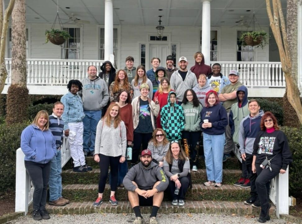 Group of people on steps of white house with porch.