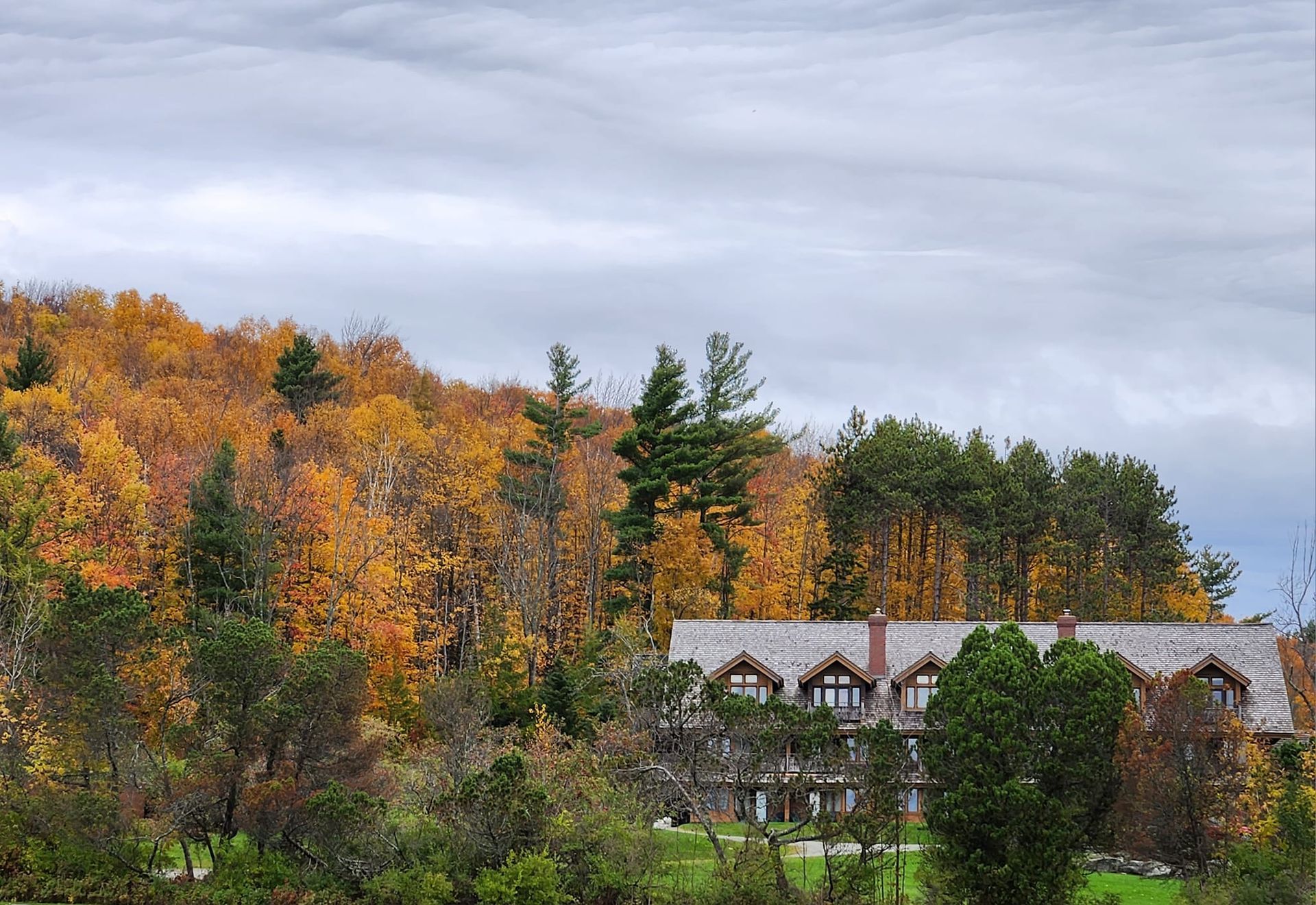 Autumn foliage frames a stone building with a slate roof.