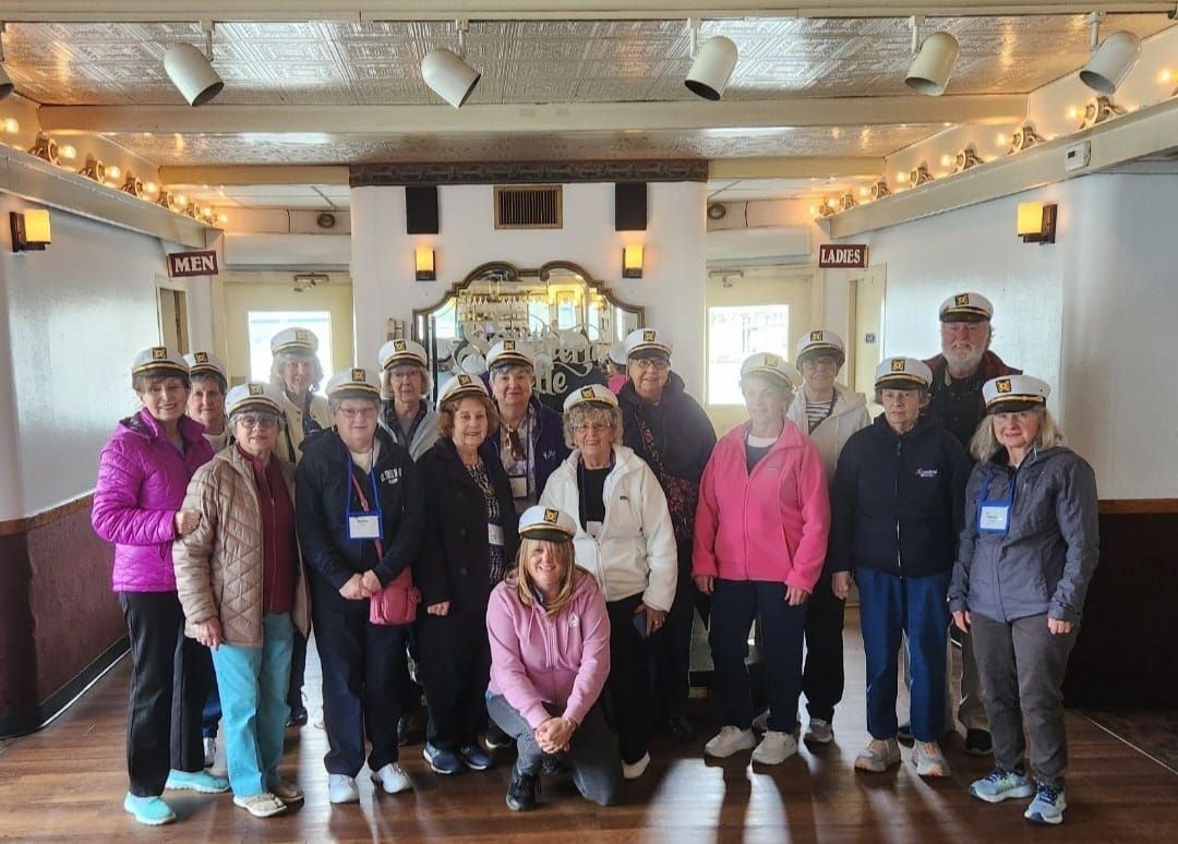 Group of people wearing hats, posed inside a decorated room with lights, likely a boat.